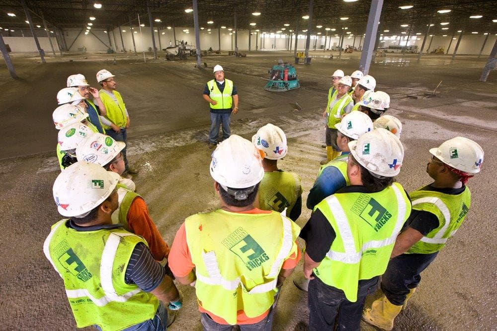 The Fricks crew gathers on an industrial flooring job site.