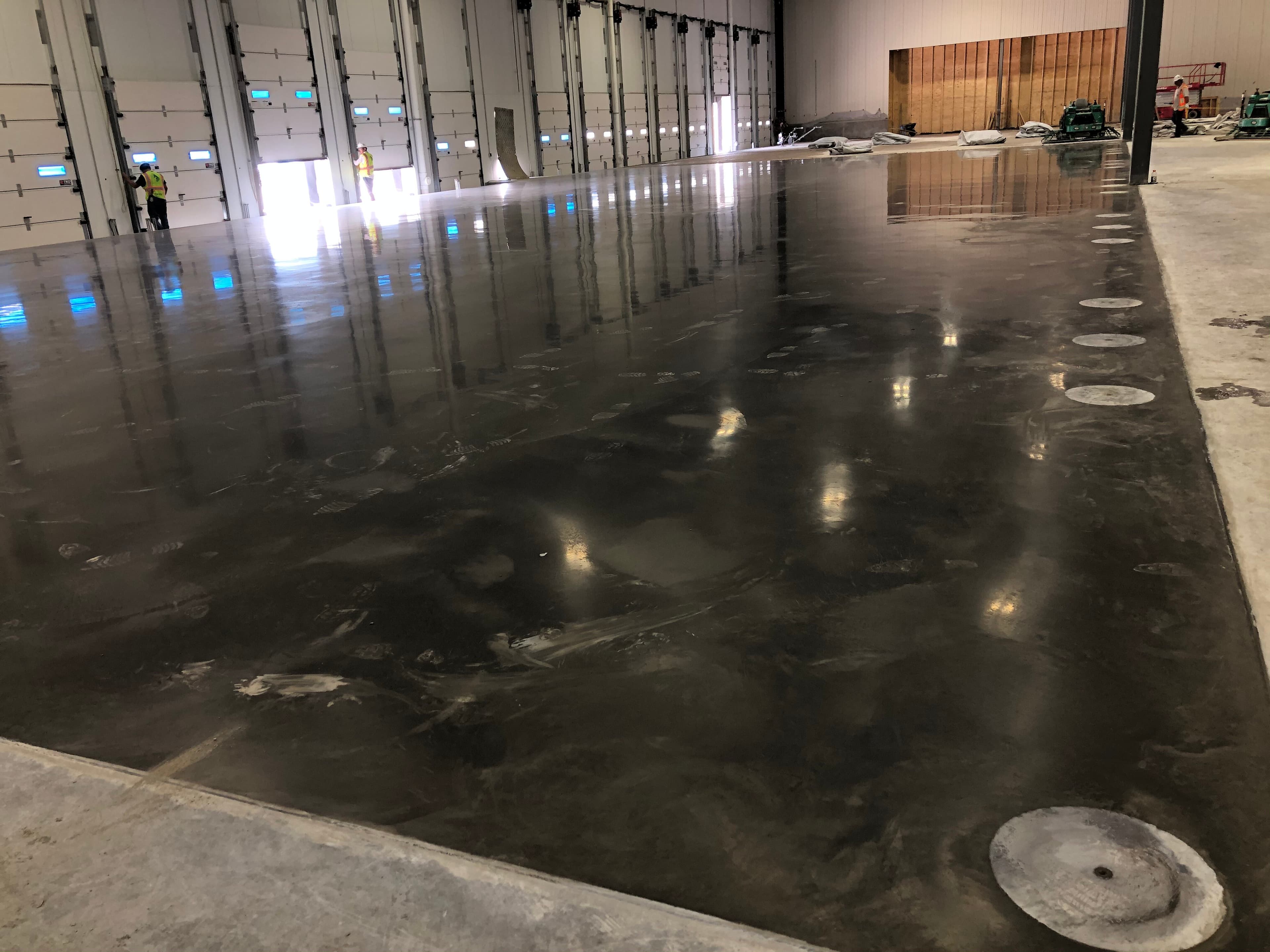 A finished concrete floor reflects the light inside a warehouse.