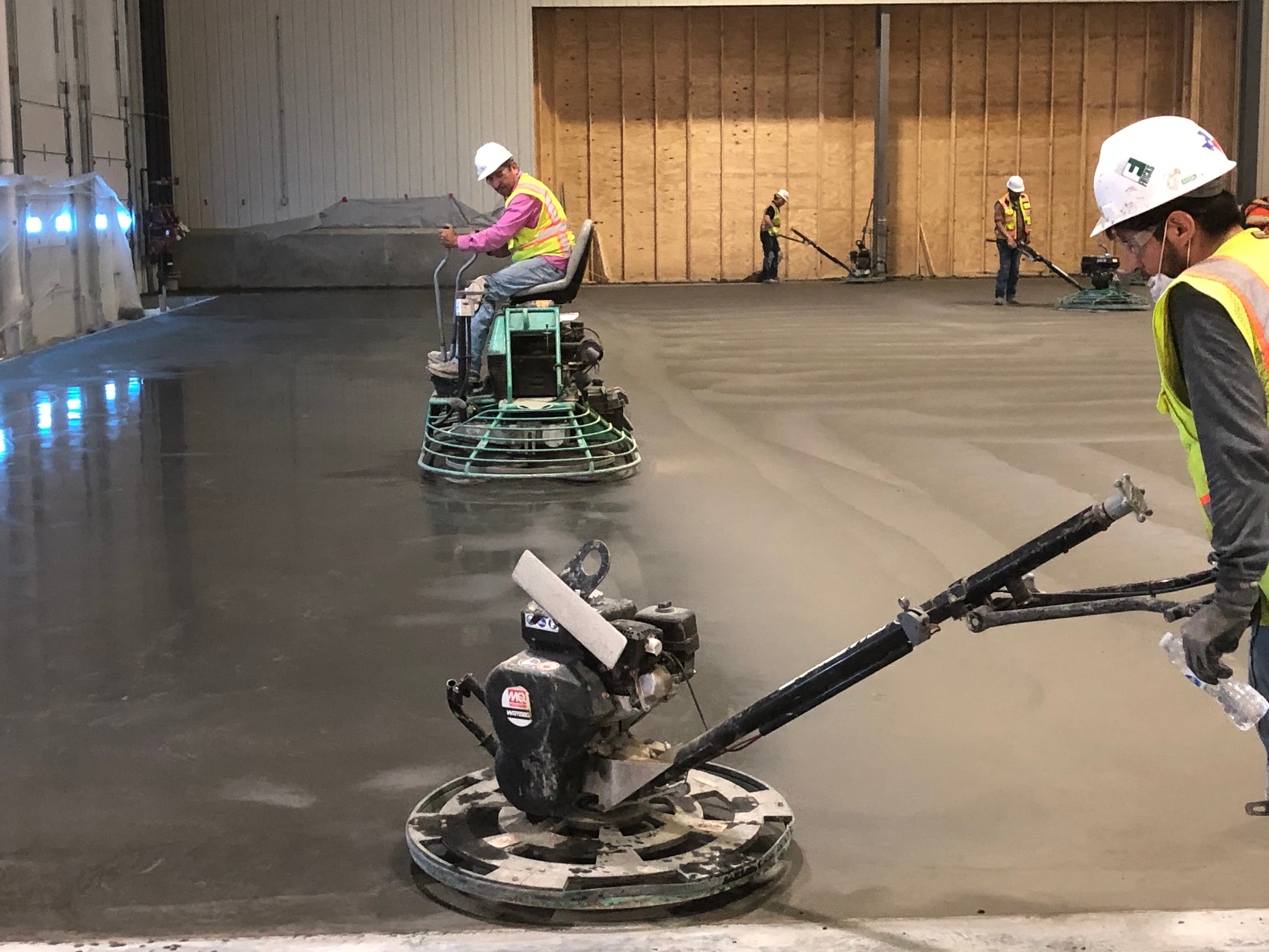 Fricks operators finish a concrete floor with riding power trowels.